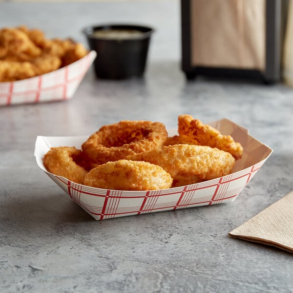 A red check paper food tray filled with fried onion rings and a cup of dipping sauce.
