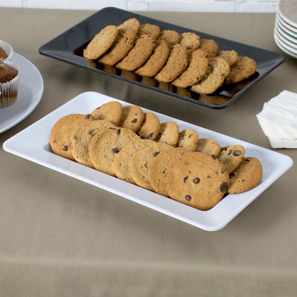 A white rectangular Milano plate with cookies and muffins on a table.