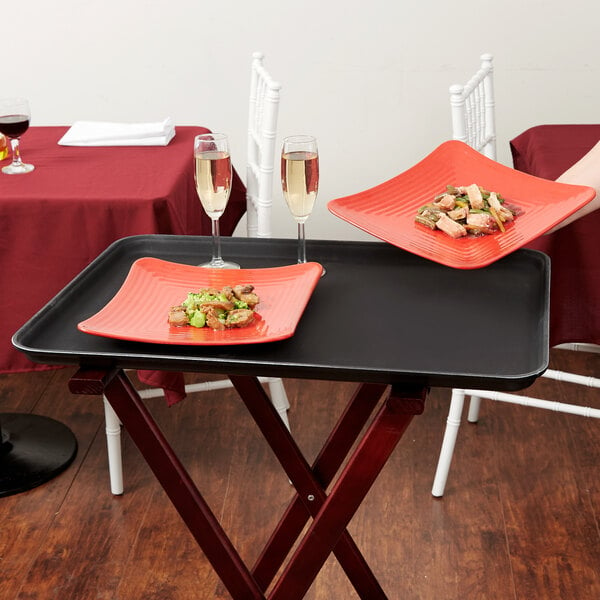 A Carlisle black non skid fiberglass serving tray with food on it.