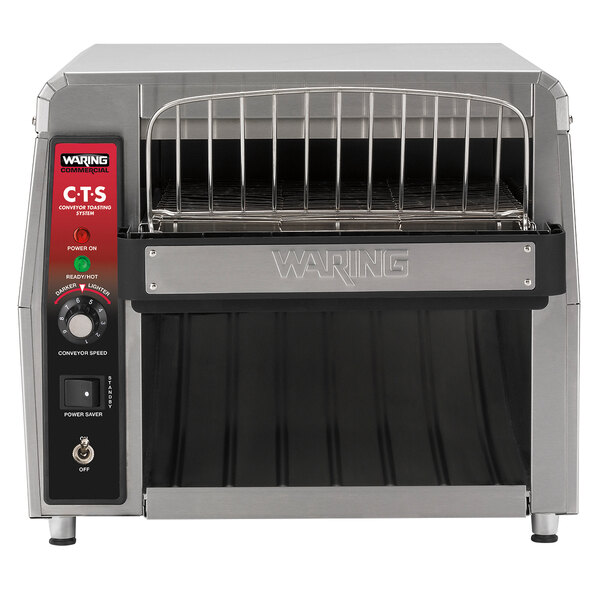 A Waring commercial conveyor toaster on a counter with a tray and rack inside.