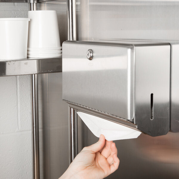 A person using a Bobrick stainless steel surface mounted paper towel dispenser.