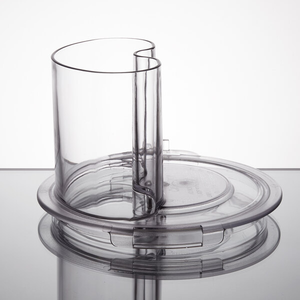 A clear plastic container with a curved bottom and a lid with a feed chute.