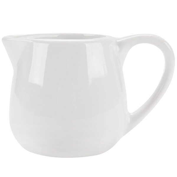 A white ceramic creamer with a handle.