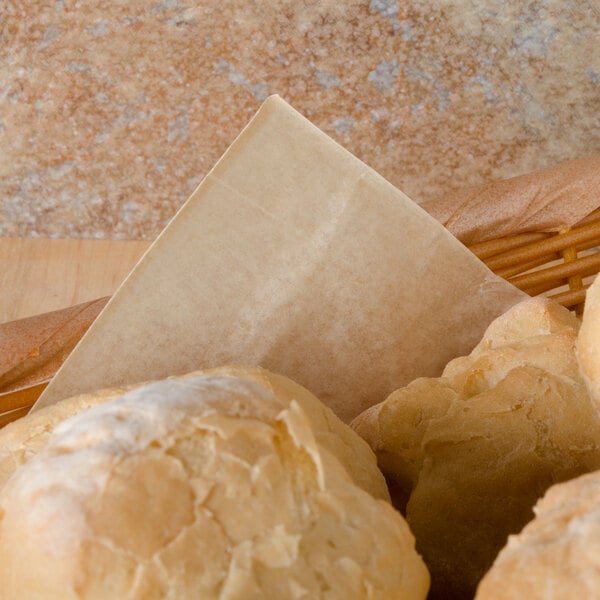 A basket of bread rolls with a piece of brown bakery tissue on top.