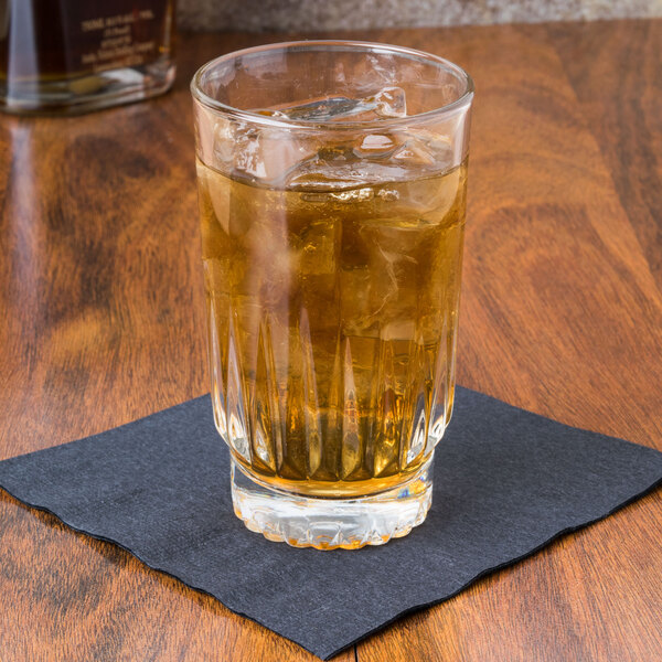 A Libbey Winchester highball glass of whiskey with ice on a table in a bar.
