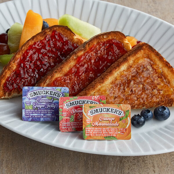 A plate of toast with Smucker's jelly and fruit.