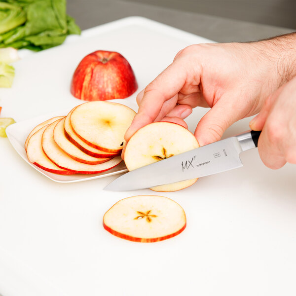A person using a Mercer Culinary Japanese petty knife to cut slices of apple.