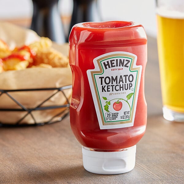 A close-up of a Heinz ketchup bottle on a table next to fries.