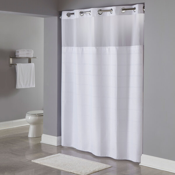 A white Hookless shower curtain with chrome rings on a shower rod.