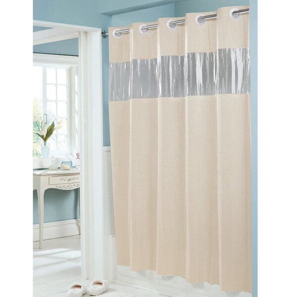 A beige Hookless shower curtain with a vinyl window and weighted corner magnets with silver trim.