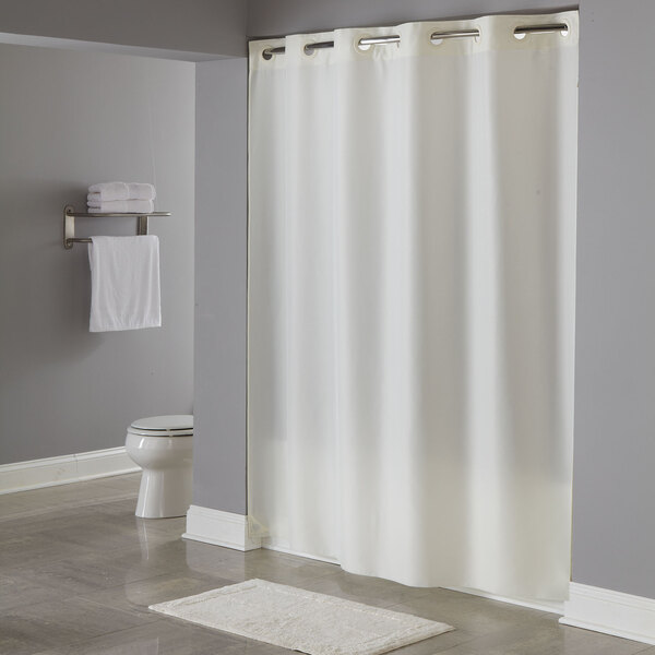 A beige Hookless shower curtain with matching rings on a shower rod.