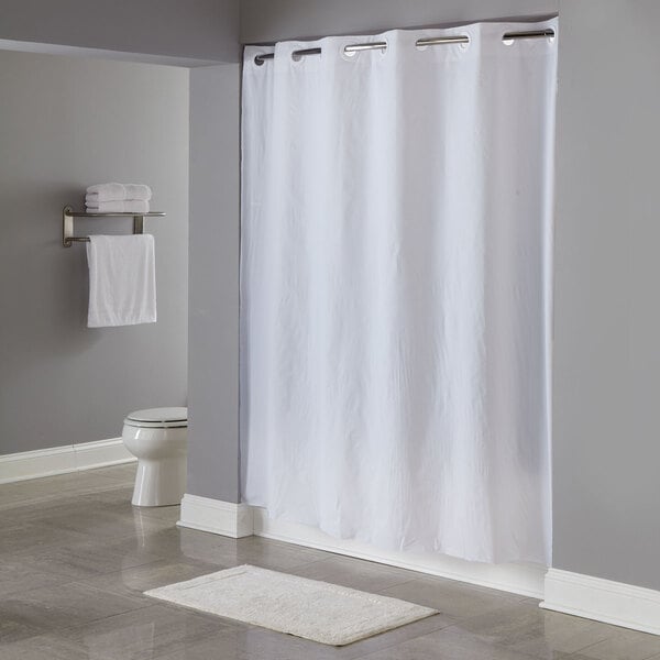 A white Hookless pin dot shower curtain hanging in a bathroom.