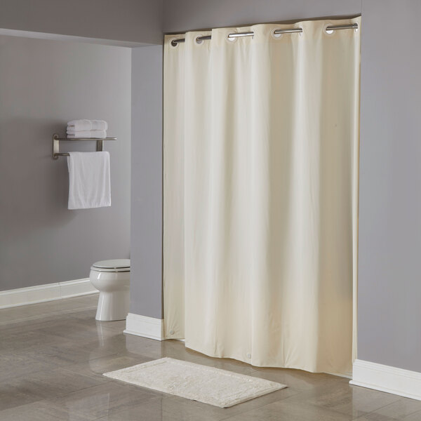 A beige Hookless shower curtain with pin dots hanging in a bathroom.