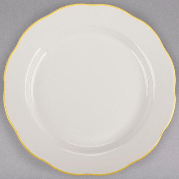 A CAC ivory china plate with scalloped edge and yellow trim.