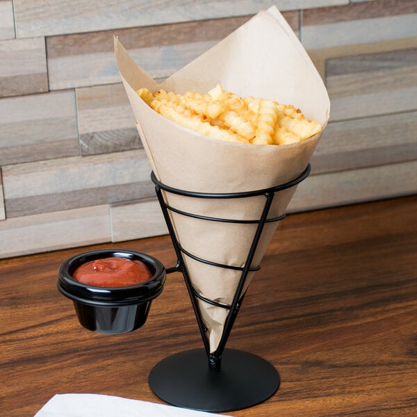A brown paper cone with a brown bag of fries and red sauce in a black metal holder.