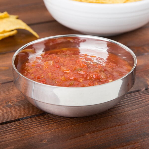 An American Metalcraft stainless steel bowl filled with salsa and chips on a table.