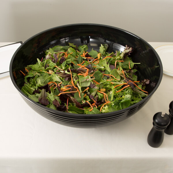 A black Cambro Camwear round ribbed bowl filled with salad on a table.