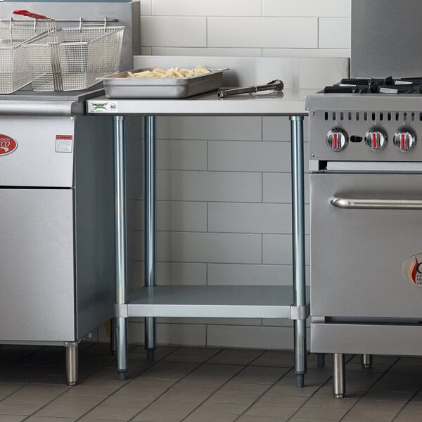 A Regency stainless steel work table with a backsplash and undershelf in a kitchen with stainless steel stoves.