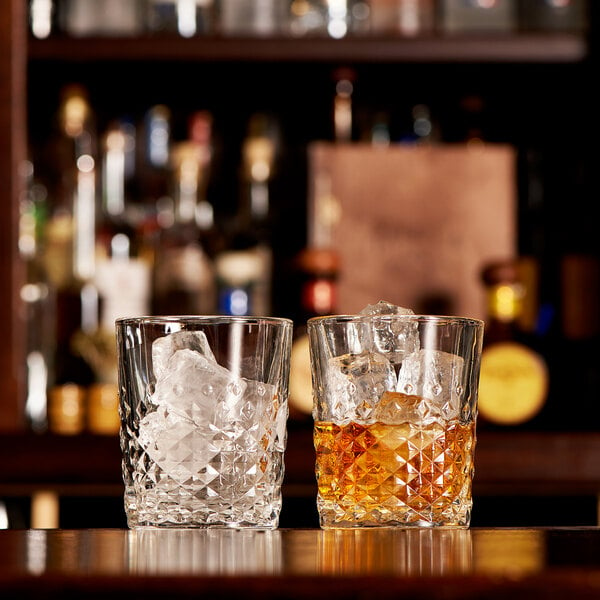Two Libbey double old fashioned glasses with ice and amber liquid.