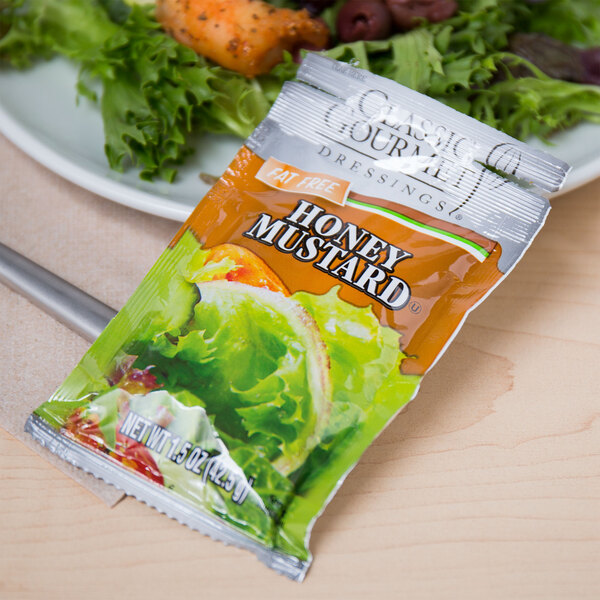 A plate of salad with a Classic Gourmet honey mustard dressing packet.