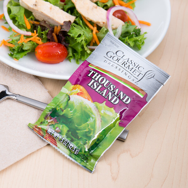 A plate of salad with a Classic Gourmet Thousand Island Dressing packet on top.