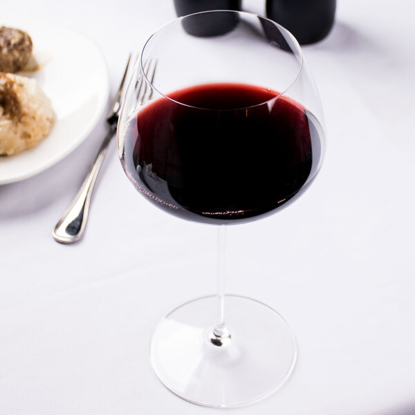 A Spiegelau Willsberger burgundy wine glass filled with red wine on a table.
