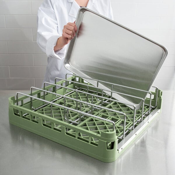 A woman in a white coat holding a Vollrath light green open end steam table pan rack.