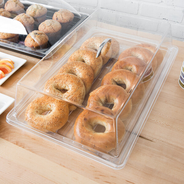 A table with a Cambro display tray of bagels and muffins on a counter in a bakery.