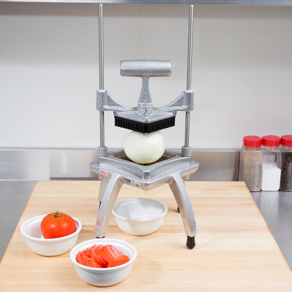 A Nemco Easy Chopper II vegetable dicer on a counter with bowls of tomatoes.