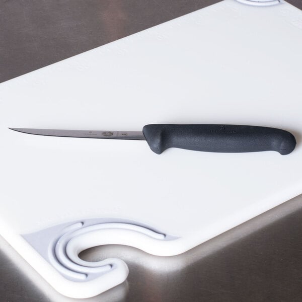 A Victorinox narrow semi-flexible boning knife on a white cutting board.