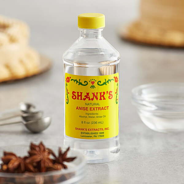A bottle of Shank's anise extract on a kitchen counter next to a spoon.