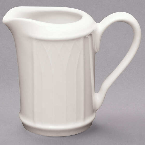 A white Homer Laughlin china creamer with a handle.