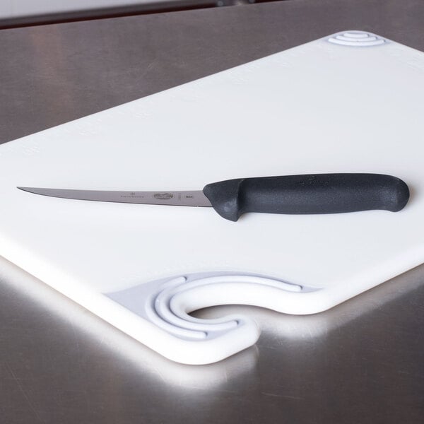 A Victorinox curved semi-stiff boning knife with a black handle on a cutting board.