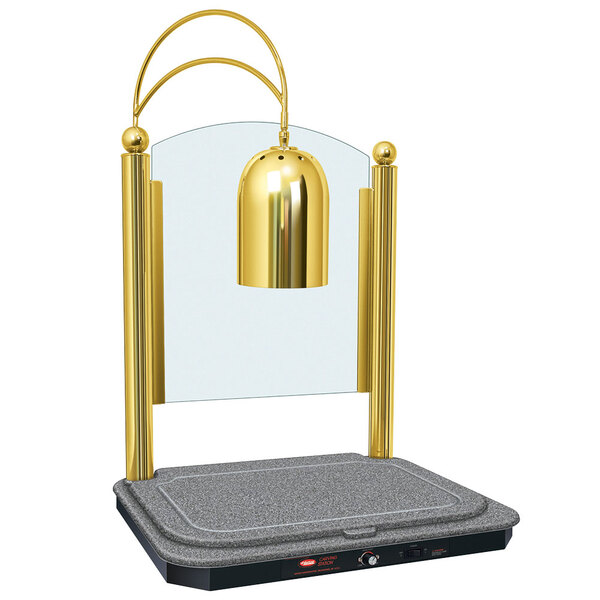 A Hatco carving station with a granite grey heated base and bright brass finish with a golden bell on a stand.