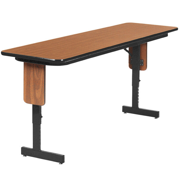 A rectangular Correll seminar table with black panel legs and medium oak top.