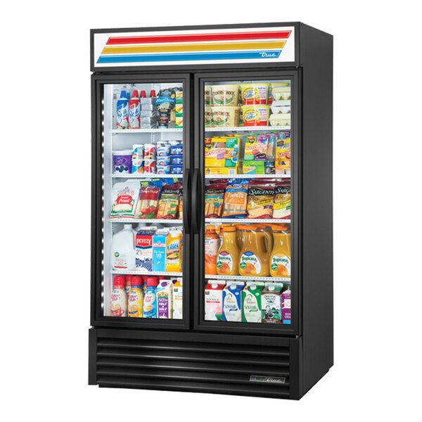 A black True refrigerated glass door merchandiser with shelves of drinks.