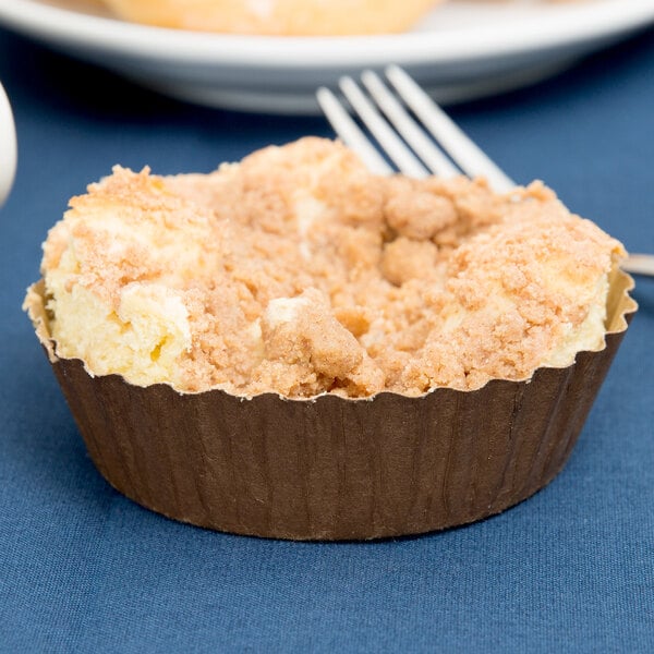 A Solut kraft paper baking cup with a muffin and a fork on a plate.