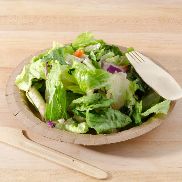 A Solut kraft paper plate with a salad and a wooden fork.
