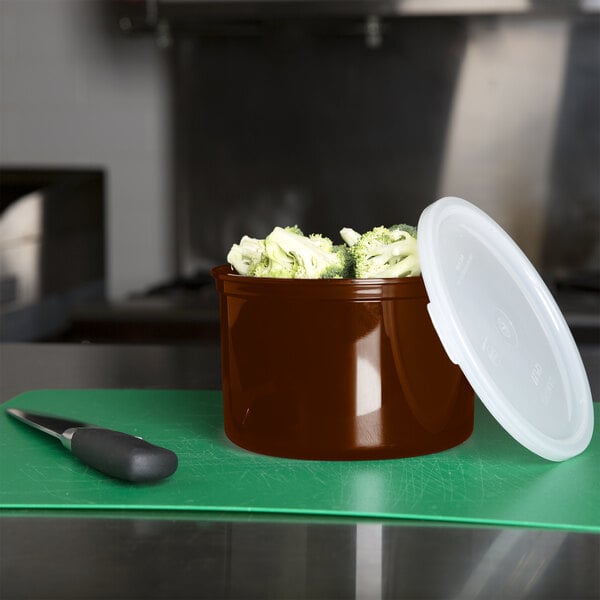 A brown Cambro round plastic crock with broccoli inside on a counter.