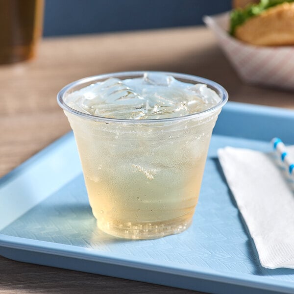 A clear Choice PET plastic cup with a drink and ice on a tray.