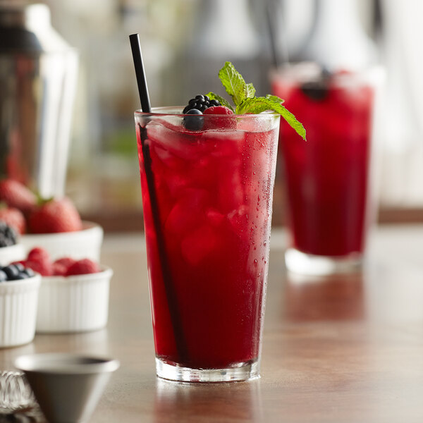 A Libbey tall pint glass filled with red liquid, ice, and garnished with mint and berries.