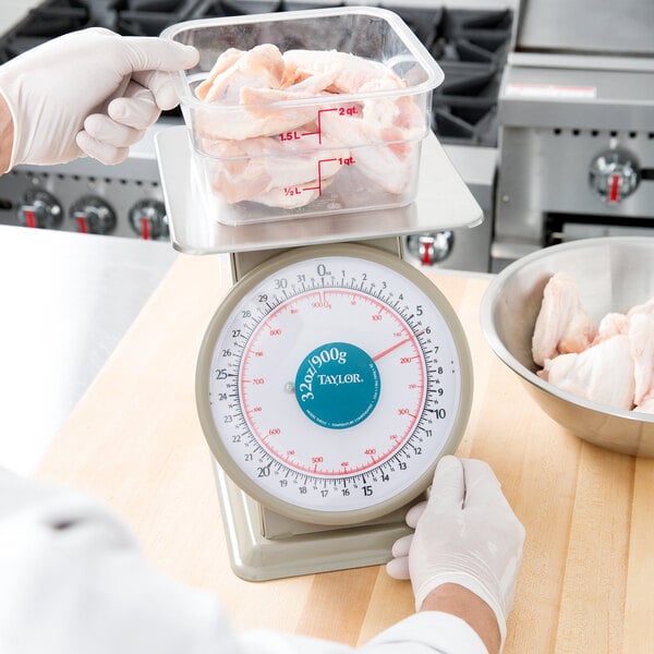 A person weighing meat on a Taylor Heavy Duty Mechanical Portion Scale.
