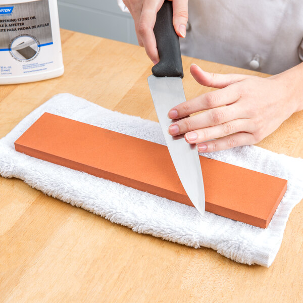 A person sharpening a knife on a white towel.