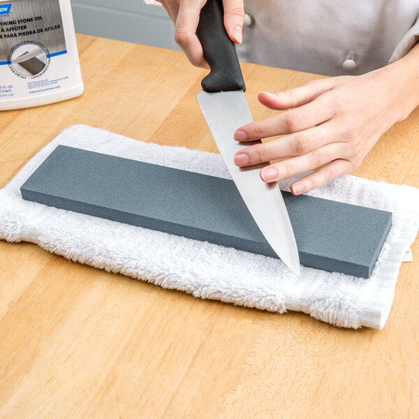 A person using a Victorinox Crystolon sharpening stone to sharpen a knife.