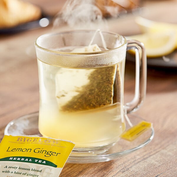 A glass mug of Bigelow Lemon Ginger Herbal Tea with a tea bag in it.
