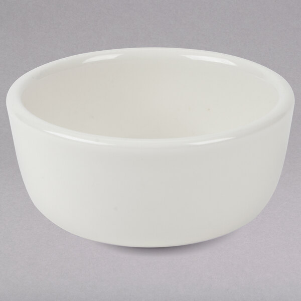 A white Tuxton china bowl with a small rim on a gray surface.
