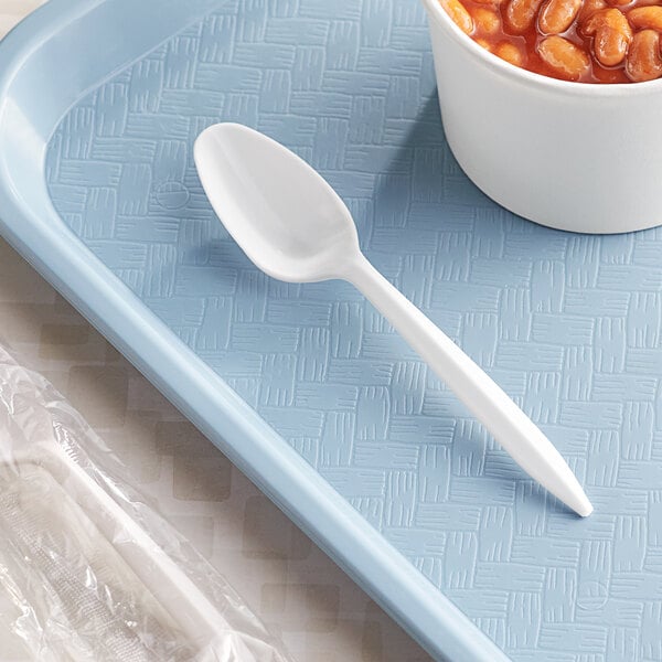 A white Choice plastic teaspoon on a blue tray next to a bowl of beans.