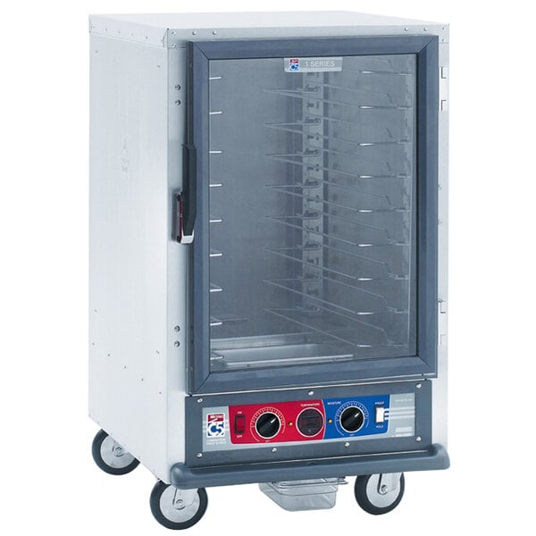 A Metro C5 1 Series heated holding cabinet with a clear glass door and wheels.