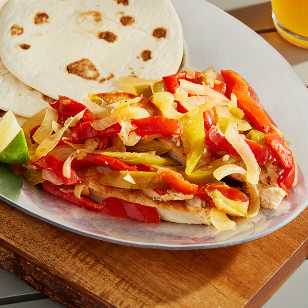 A plate with tortillas, vegetables, and meat including mixed pepper strips with onions.