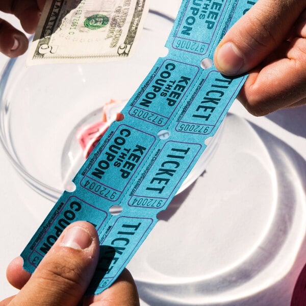 A pair of hands holding blue Carnival King raffle tickets.